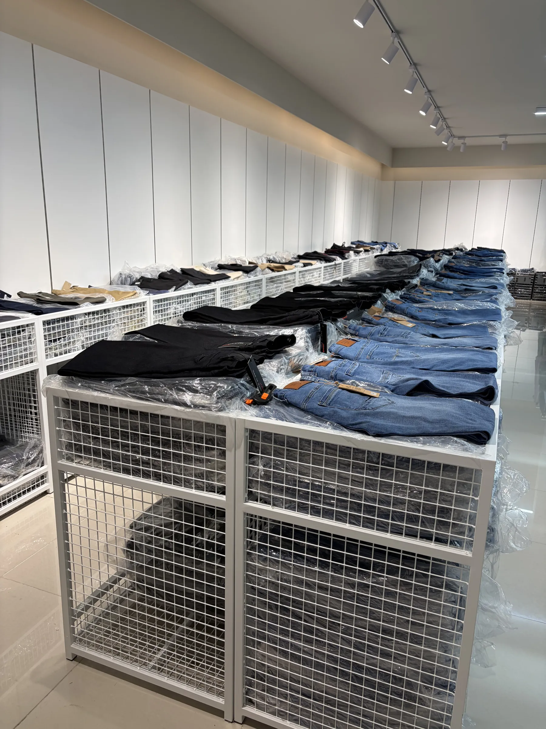 HUANG'S stockroom — denim jeans laid out on mesh bins along the warehouse aisle